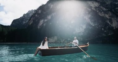 Romantik Çift portre göl adam kürek ahşap tekne ve onun kız bacakları suda oynarken ortasında.