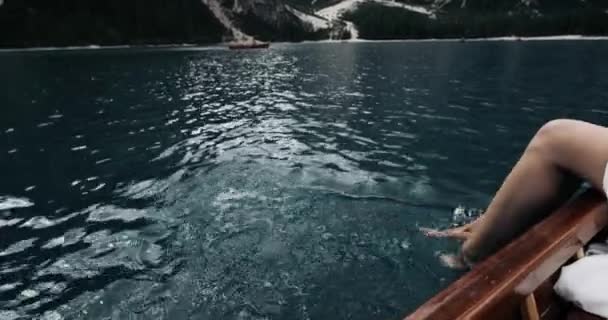 Primo piano giovane donna nella barca di legno giocare con le gambe nel lago scintillante. 4k — Video Stock