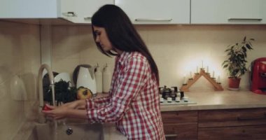 Genç kadın mutfakta sebze yıkama sonra mutlu mutlu git yemek yapmak için