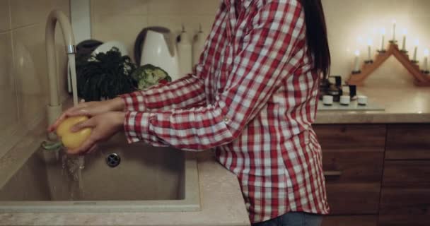 Женщина крупным планом готовит овощи к ужину на кухне, стирает их у раковины. 4k — стоковое видео