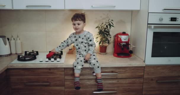 Un niño muy lindo se sienta en la cocina jugando con una verdura y sonriendo. épica roja — Vídeo de stock