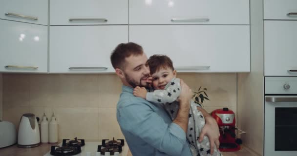 Sonriendo joven papá jugando con amor con su bebé en la cocina — Vídeos de Stock