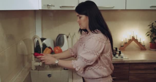 Молодая женщина готовит к ужину бобовые, стирая их у раковины на белой кухне. . — стоковое видео
