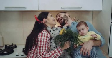 Genç aile çocukları ile birlikte mutfakta sebze ile oynuyor