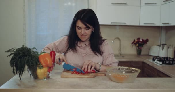 Donna felice tagliare le verdure per preparare il cibo lo sfondo è la cucina bianca — Video Stock