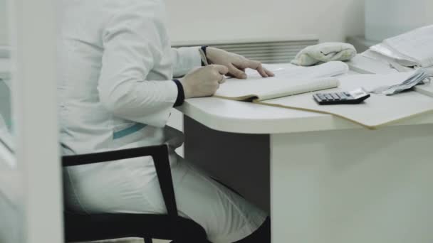 Лаборант сидит на столе и что-то пишет. . — стоковое видео