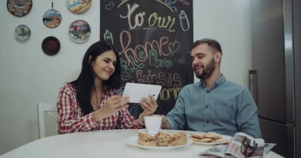 Esposa feliz dando o cartão de crédito para o marido e juntos estão encomendar algo do tablet, no final eles estão se beijando. 4k — Vídeo de Stock