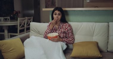 Genç kadın patlamış mısır yemek tv izliyor ve çok heyecanlı olduğunu.