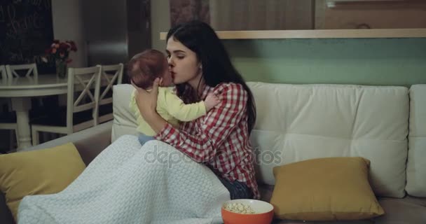 Joven madre pasando tiempo con su bebé sentado en el sofá en la sala de estar. 4k — Vídeos de Stock