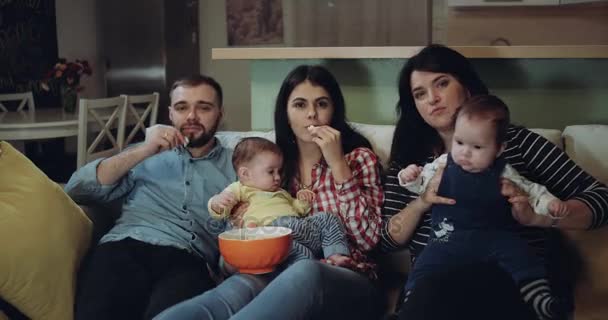 Grande família com seu bebê assistindo TV e desfrutar do tempo juntos comendo as pipocas. 4k — Vídeo de Stock