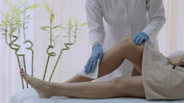 Spa 中心的美容师为脱毛准备女人的腿。4k — 图库视频影像