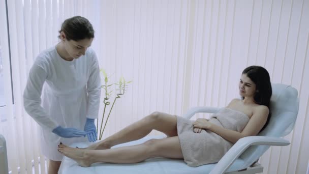 Um esteticista de salão de beleza fazendo depilação de cera, procedimento doloroso em seu paciente . — Vídeo de Stock