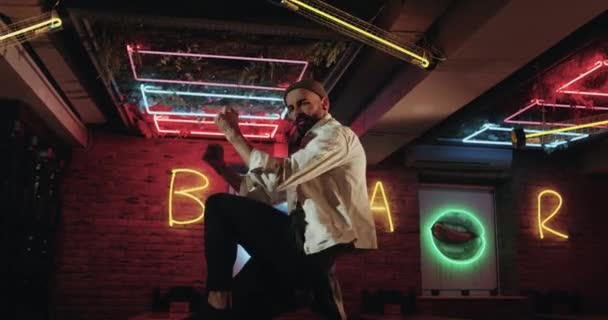 Fantastische donkere café met kleur verlichting, jonge mannen dansen op de bar tafel. rode epos — Stockvideo