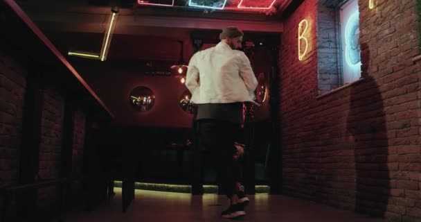 En el bar joven en la chaqueta blanca bailando fondo feliz con luces de color parpadeantes — Vídeo de stock