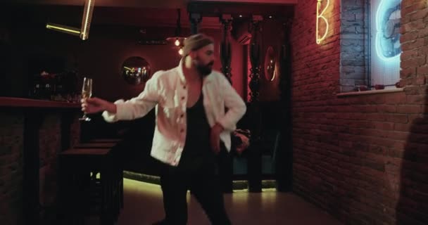 Харизматичные мужчины в баре с цветными огнями танцуют счастливо и пьют шампанское — стоковое видео