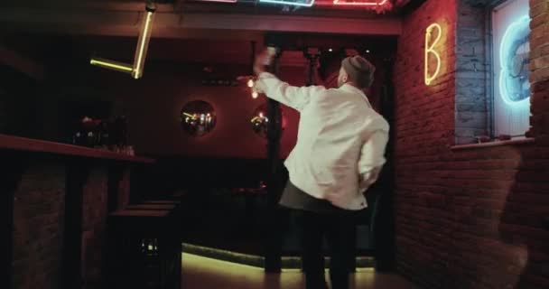 Homme dansant dans le bar avec des lumières étonnantes, il tient le smartphone et prend des photos — Video