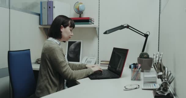 Junge Frauen im Büro sitzen an ihrem Schreibtisch und tippen auf Tastatur in Notizbuch. rotes Epos — Stockvideo