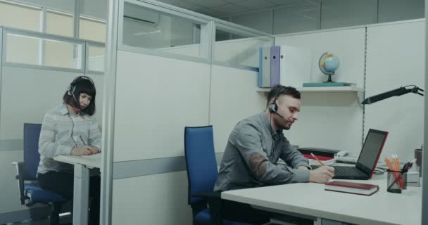 Operadores del centro de atención al cliente hablando con el cliente usando los auriculares — Vídeos de Stock