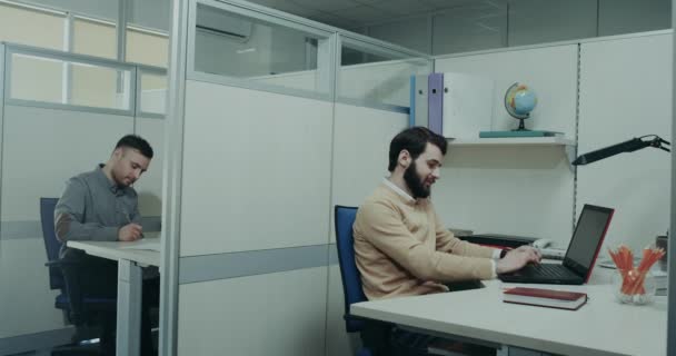 Au bureau, deux ouvriers assis sur leur bureau, tapant sur le clavier, heureuse jeune femme souriante lui servent un peu de travailleur avec un café. 4k 