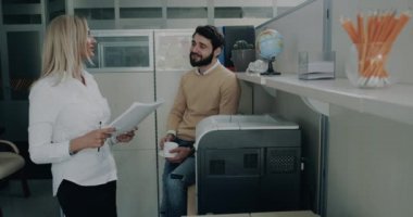 İki office çalışan kadın ve erkek muhabbet ve aynı zaman erkek birkaç belge yazdırma.