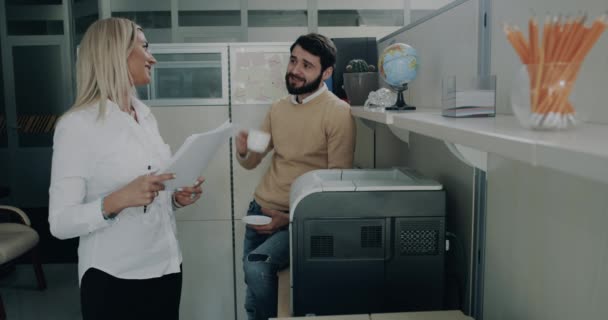 Młoda kobieta z młodym mężczyzną mają wielkie rozmowy w biurze do drukowania dostać jakieś papiery. — Wideo stockowe