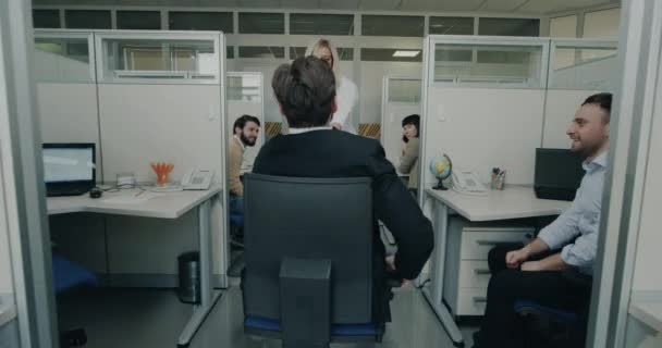 Twee collega spelen met een stoel in het kantoor op hun werkplek — Stockvideo