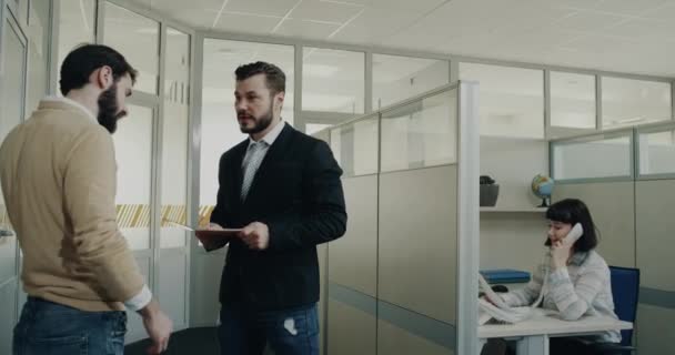 Två kollegor har en konversation i office hallen — Stockvideo