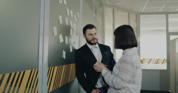 Dvě kolegyně muž a žena si dělat poznámky a držet je na zdi kanceláře. — Stock video