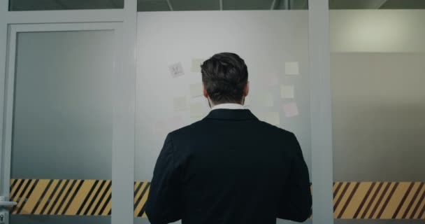 У офісному коридорі молоді чоловіки пишуть нотатки і наклеюються на стіну — стокове відео