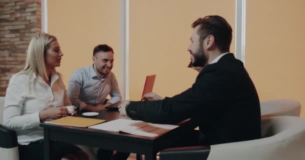 Los colegas de oficina tomando un descanso en la mesa de café en el centro de negocios, sonriendo tener una buena conversación . — Vídeos de Stock