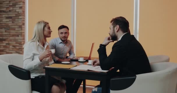 Parceiros de negócios conversam na mesa de café, bebendo algo da xícara — Vídeo de Stock