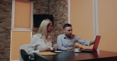 Kafede kahve içme ve dizüstü bilgisayar seyir bir şey hakkında konuşan iki ofis çalışanı