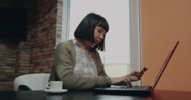 Kısa saçlı genç kadın portre sipariş kartı kullanarak dizüstü bilgisayarda bir şey kesmek