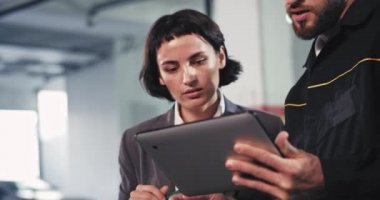 Güzel bir iş kadını olan kameraman tamirciye yakın çekim. Servis otomobili içinde elektronik tablet kullanarak arabanın sorununu analiz ediyor.
