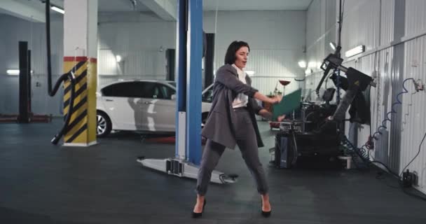 Όμορφη γυναίκα σε ένα κοστούμι χορό ευτυχισμένη αφού κάνει μια μεγάλη συμφωνία σε μια σύγχρονη υπηρεσία auto κέντρο — Αρχείο Βίντεο