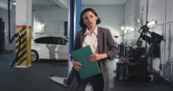 在服务的中途，汽车中心的工作人员非常有魅力的女士，和一些顾客做完交易后，穿着西装跳着滑稽的地图 — 图库视频影像