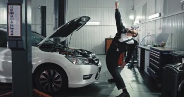 Modern ve büyük bir servis otomobili ile iş yerinde çekici bir tamirci ara verip kameranın önünde komik bir şekilde dans etmeye başlıyor.