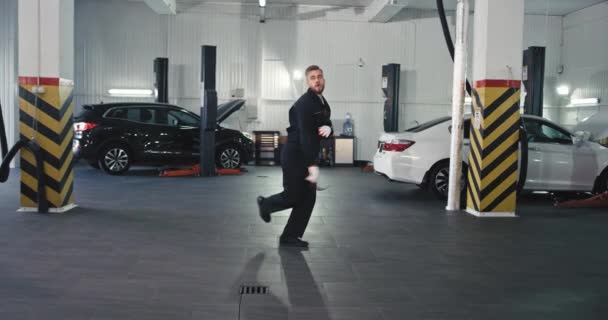 Um bom mecânico lo todos equipados dançando na frente da câmera muito animado e feliz, enquanto ele trabalha sobre um carro — Vídeo de Stock