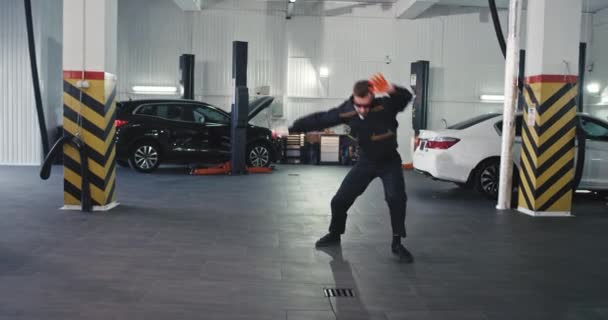 Happy worker mechanic man in a garage dancing excited after he finished his working day — Stock Video