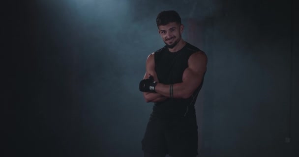 Улыбающийся харизматичный сильный спортсмен в спортивной одежде, смотрящий в камеру и позирующий в крестообразном классе — стоковое видео