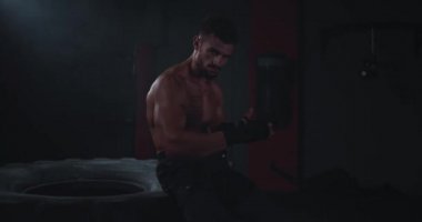 Vücut geliştiren adam eğitimine başlamadan önce bandajları eline sarar ve konsantre gözlerle kameraya bakar.