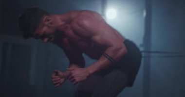 Çapraz fitness sınıfında güçlü vücudu olan çekici bir adam sıkı bir antrenman yapıyor. Konsantre olurken karın kaslarını tutan elastik bir bantla koşuyor.
