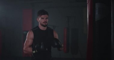 Atletik genç adam yoğun bir antrenman yapıyor. Yumruk torbasında boks yapıyor.