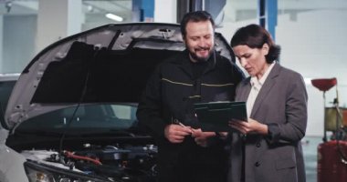 Olgun tamirci ve ofis yöneticisi araba tamircisinde sohbet ederler. Arabayı tamir etmeye başlamadan önce bazı evrakları imzalarlar.