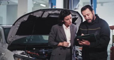 Otomobil servisinden çekici bir bayan yöneticiyle görüşüp belgeleri inceleyip, çok iyi sonuçlandığına dair imzalar atıyorlar.