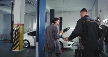 Yakışıklı tamirci ve arabanın sahibi ya da müşterisi. Garajda motoru kontrol eden harika bir kadın.