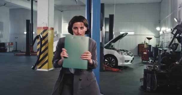 Devant la caméra dans un grand service auto centre dame avec une carte verte et costume danse heureux après avoir signé quelques documents et faire beaucoup — Video