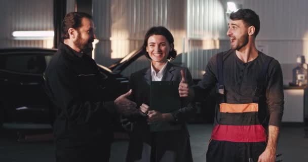 Porträt von drei Arbeitern aus dem Autoservice-Center, die direkt in die Kamera blicken und sich glücklich fühlen — Stockvideo