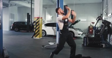 Modern araba tamircisi genç tamirci arabayı tamir ederken heyecan içinde dans ediyor. Keyfi yerinde ve işte harika bir gün geçiriyor.