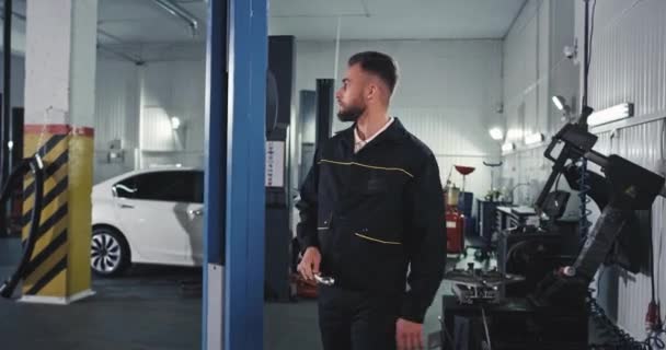 Goed uitziende man monteur in een moderne dienst auto dansen charismatisch terwijl hij het controleren van de auto — Stockvideo